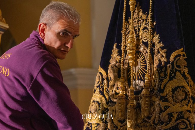 Entrevistador conversando con el vestidor de Nuestro Padre Jesús Nazareno, mostrando detalles de la túnica en Alcázar de San Juan. Fotografía de La Cruz de Guía – Ikonox.