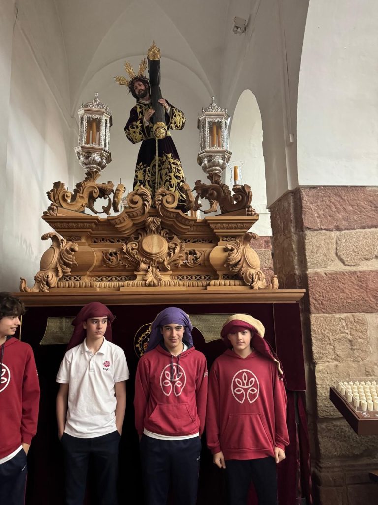 Niños participando en la jornada educativa de la Hermandad de Nuestro Padre Jesús del Perdón, con la imagen de los titulares de la hermandad al fondo.